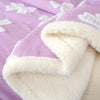 A folded plush jacquard throw blanket in lavender and white floral patterns.