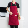 A woman wearing a deep red waterproof canvas chef apron over a black shirt, standing in a kitchen setting.