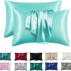 Un juego de fundas de almohada de seda satinada en varios tonos, incluyendo coral, verde azulado y púrpura.