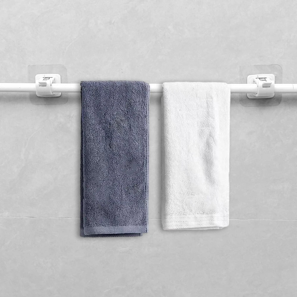 Two towels, one dark gray and one white, are hanging on a white curtain rod with adhesive clips.