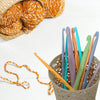 A collection of colorful plastic crochet hooks in various sizes stored in a woven basket.