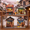 A display of three detailed Japanese miniature book nooks or shops built from wood and paper.