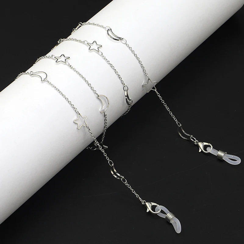 Silver chain necklace featuring a star and moon pendant on a white wrist.