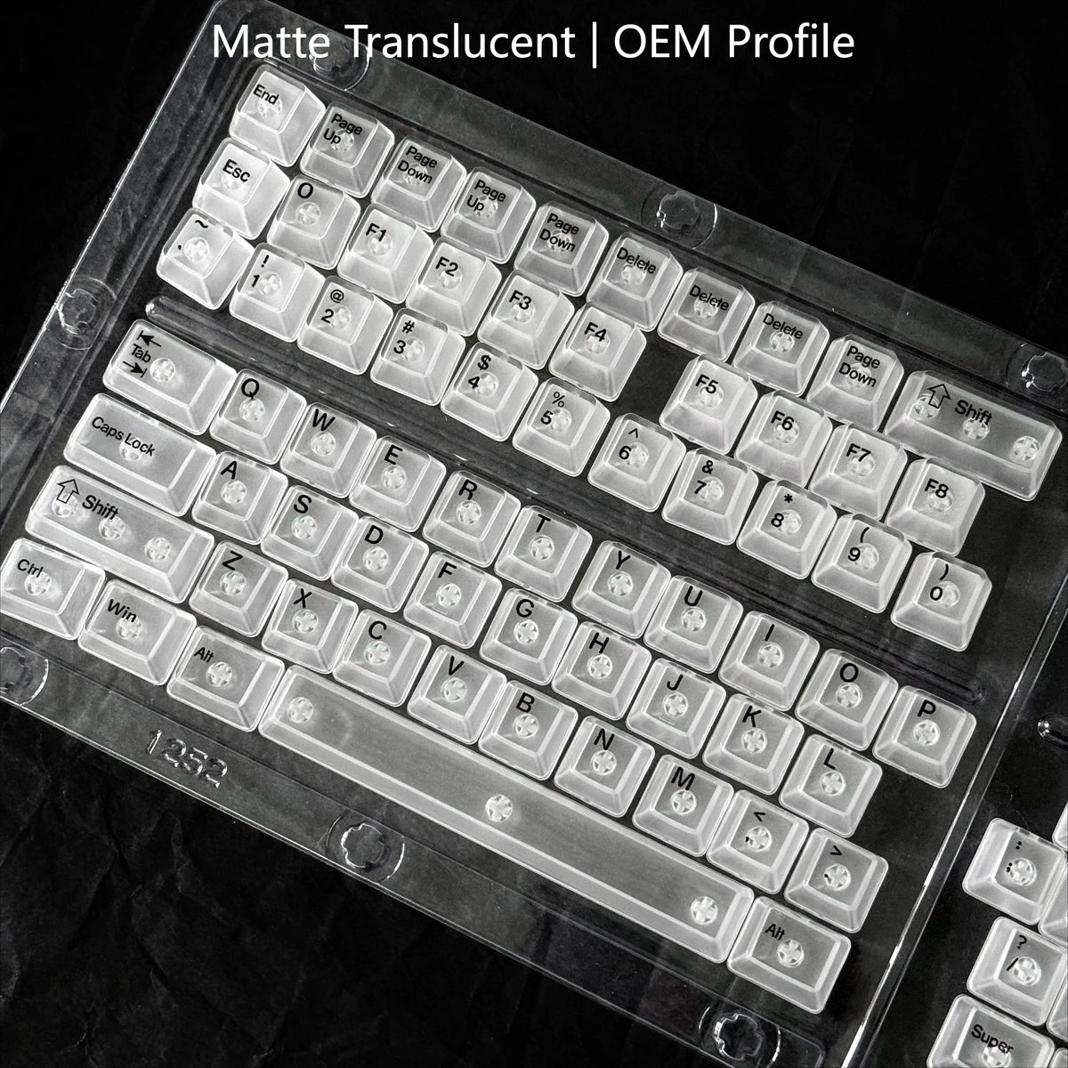 A close-up view of a translucent OEM profile keyboard with white keycaps resting on a dark surface.