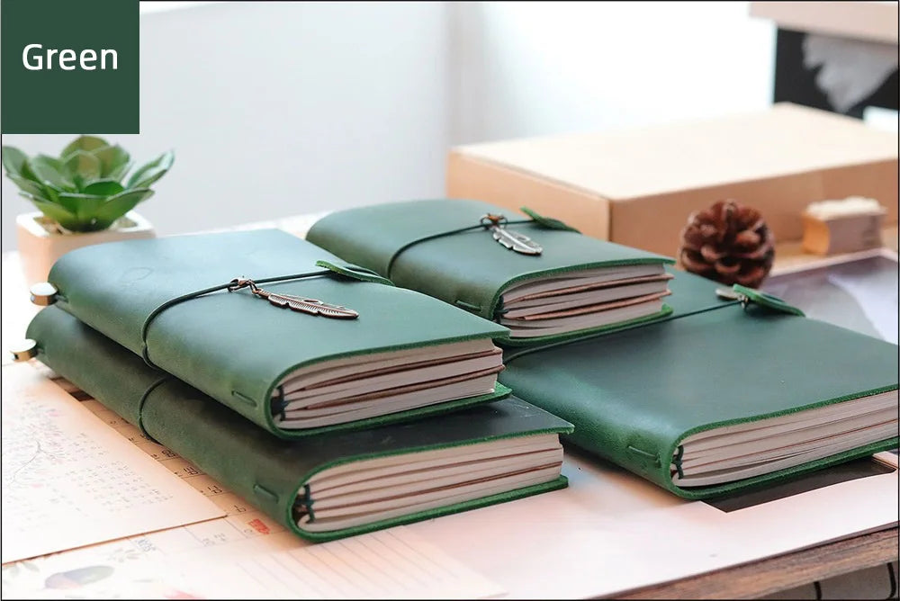 A stack of green handcrafted genuine leather refillable journals resting on a light surface.