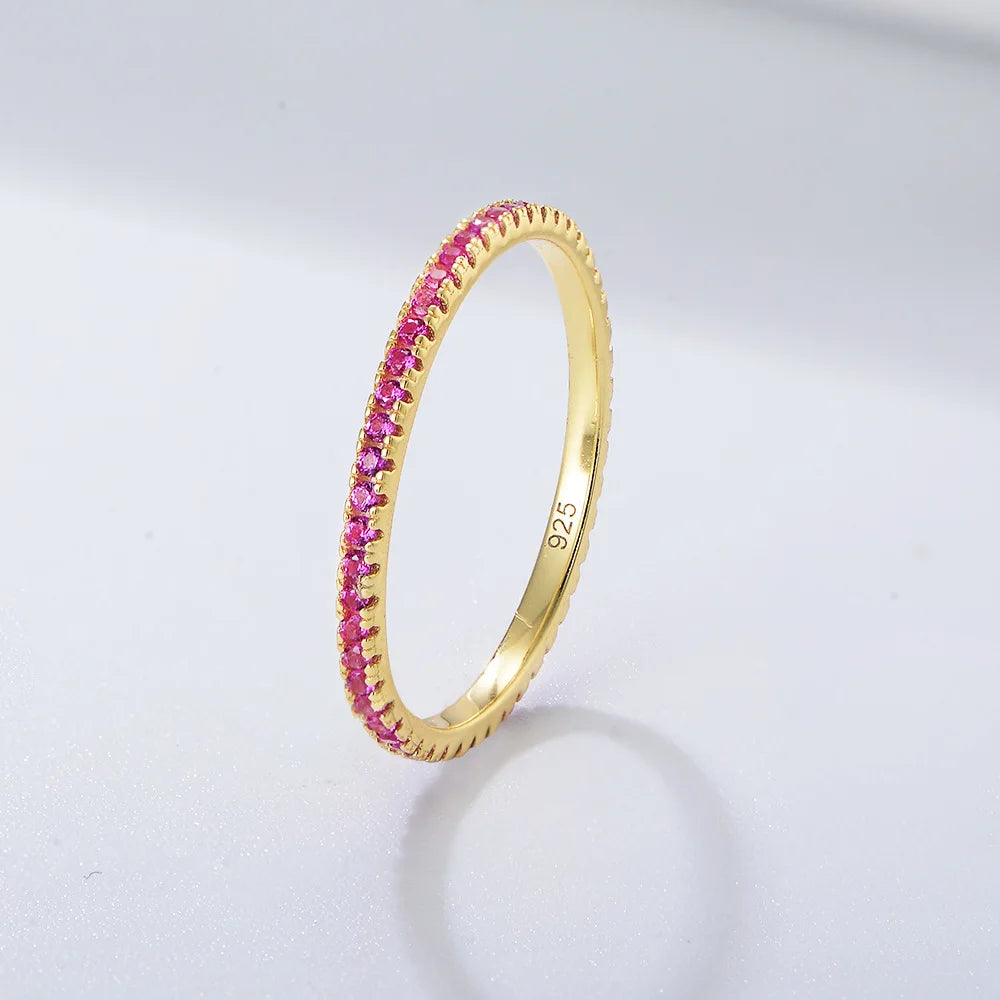 A gold-plated ring with a band set with pink CZ stones, shown on a white background.