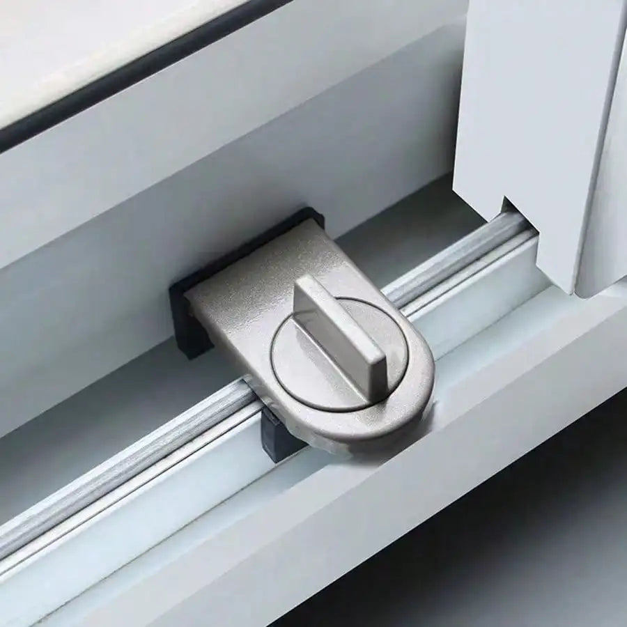 A close-up view of a silver no-drill sliding door lock mechanism installed in a white frame.