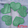 A set of five green glitter heart iron-on embroidered patches on a gray denim fabric.