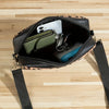 A black leopard print crossbody bag with a flap, showing an interior compartment holding a white card and a green pouch.