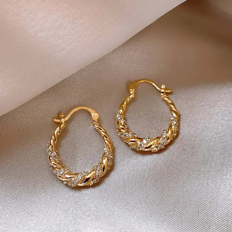 Gold twisted zircon hoop earrings displayed on a neutral background.