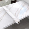 Roll of white marble peel-and-stick wallpaper showing natural veining on a light countertop surface.