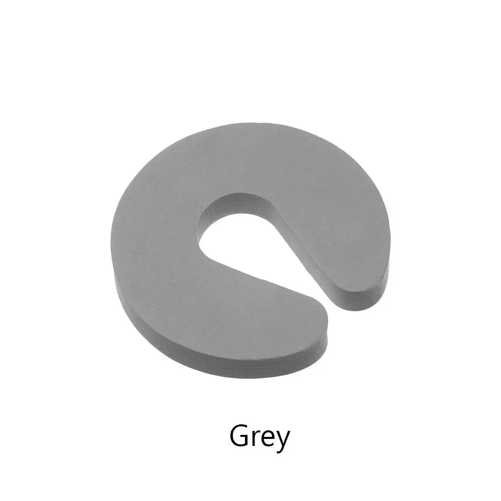 A grey foam door stopper with a curved shape designed for finger pinch protection.
