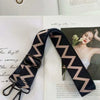 A close-up of a black and beige patterned fabric strap for an elegant handbag.