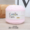 Pink cotton yarn skein labeled as Cotton Yarn 100g, shown on a wooden surface.