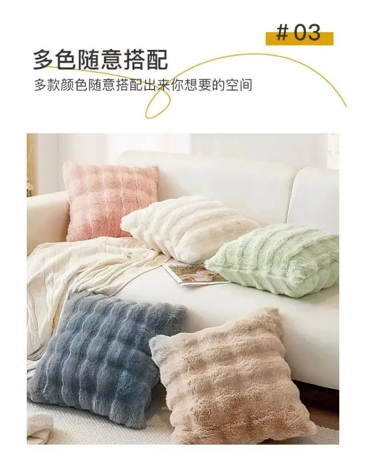 A collection of various colored plush decorative pillow covers displayed on a white sofa.
