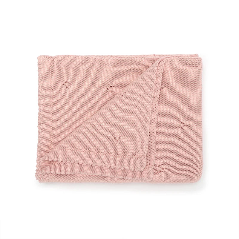 A folded soft pink cotton baby blanket with a breathable knit texture.