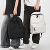 A person is holding a white minimalist canvas backpack with black accents and dark pants.