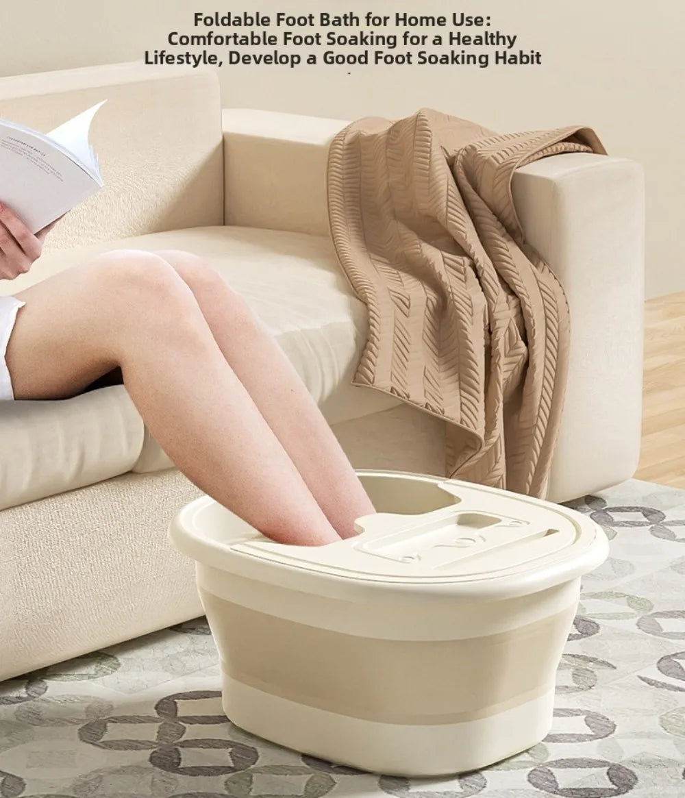 A beige foldable foot bath tub is shown being used by a person on a sofa, with a towel draped nearby.