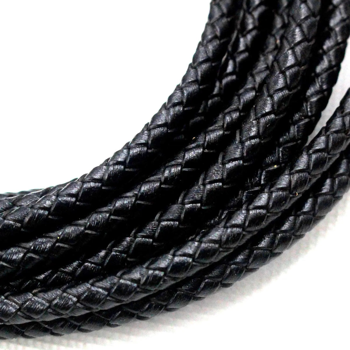 A close-up of black braided leather cord for jewelry making coiled together.