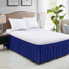 White bedding with a royal blue elastic wrap-around bed skirt and ruffles on a bed.