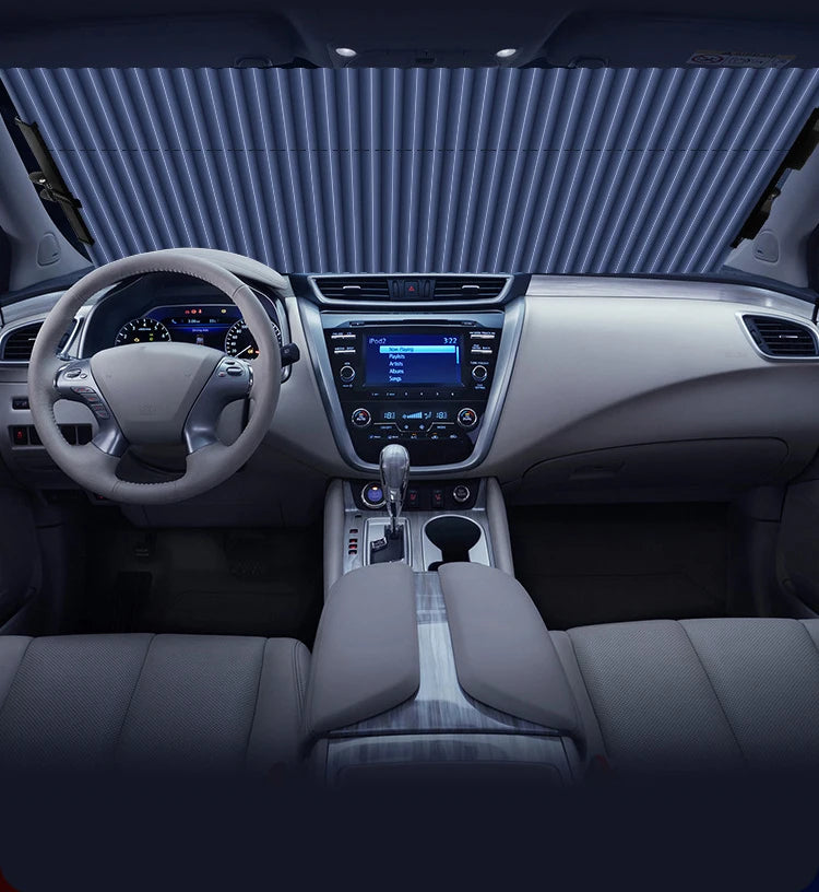 Interior view of a car showing the steering wheel, dashboard, and center console with a sunshade visible on the windshield.