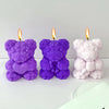 Three silicone rose bear molds in purple and pink are displayed with lit candles.