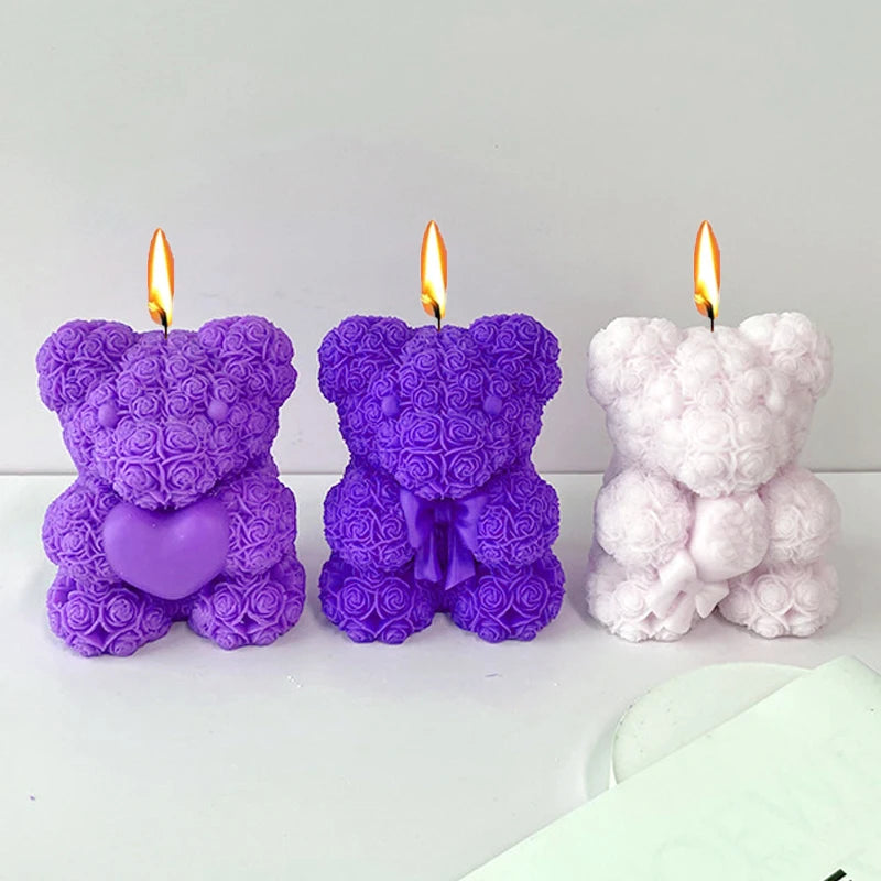 Three silicone rose bear molds in purple and pink are displayed with lit candles.