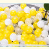 A large plastic container filled with a mix of yellow and white colorful ball pit balls for toddlers and kids.