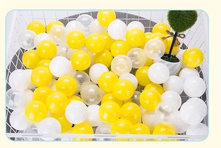 A large plastic container filled with a mix of yellow and white colorful ball pit balls for toddlers and kids.