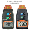 A black digital laser tachometer device with a yellow warning triangle and an orange display showing 956.3 RPM.