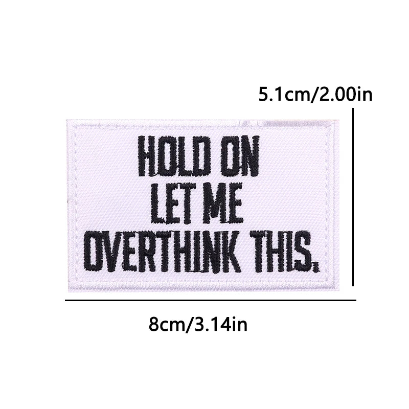 A rectangular black embroidered patch with white text that reads HOLD ON LET ME OVERTHINK THIS.