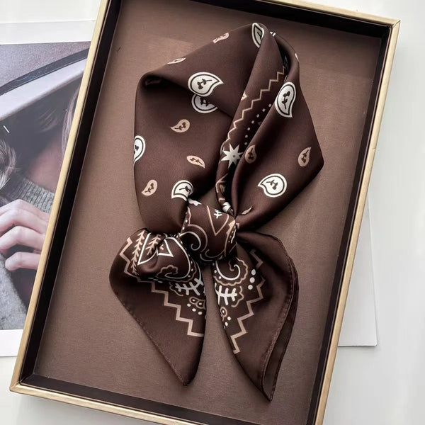 A dark brown bohemian paisley printed scarf tied in a bow displayed in a wooden frame.