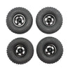 Four black RC car upgrade wheels with metal rims and soft tires shown from above.