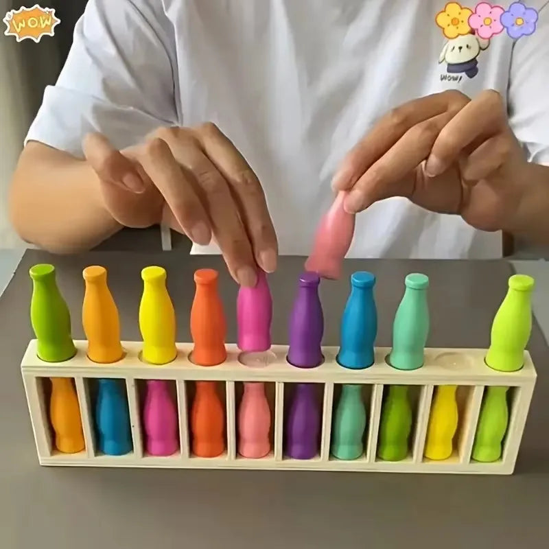 A person's hands are placing colorful plastic bottles into a wooden grid for a color match memory game.