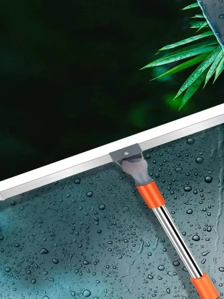 A silicone squeegee broom with an aluminum handle is shown cleaning water droplets off a glass surface.