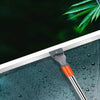 A silicone squeegee broom with an aluminum handle is shown cleaning water droplets off a glass surface.