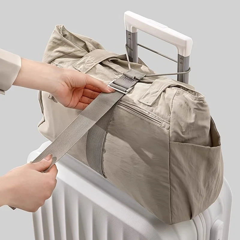 A hand is adjusting an adjustable luggage strap with a quick-release buckle on a beige canvas bag placed on a white radiator.