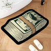 A black non-slip bathroom rug featuring a print of US dollar bills and a portrait of a historical figure on a wooden floor.