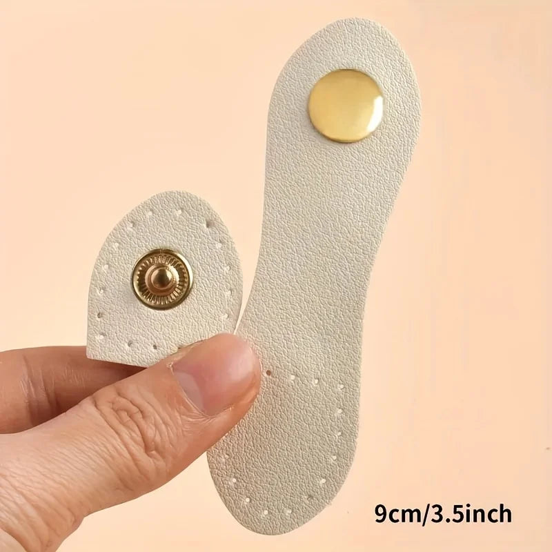 A set of eight light beige leather buckle clasps with gold accents shown being held by a hand.