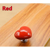 A red heart-shaped toilet flush button resting on a wooden surface.