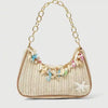 A beige woven straw shoulder bag decorated with colorful ocean shell charms.