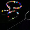 A set of seven colorful beads and a needle for jewelry making