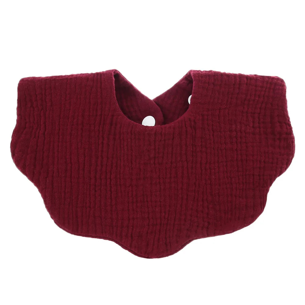 A deep burgundy knitted baby bib in a bandana style with a cutout for the neck.