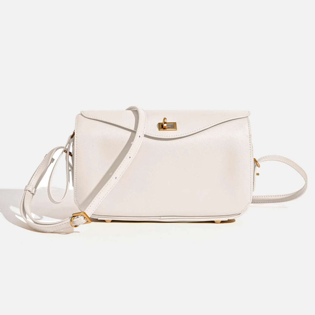 A light beige genuine leather square crossbody bag with gold hardware and a matching strap.