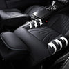 Black full coverage PU leather car seat covers with white stitching and textured upholstery shown in a vehicle interior.