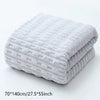 A stack of light gray coral velvet bath towels folded neatly on a white surface.