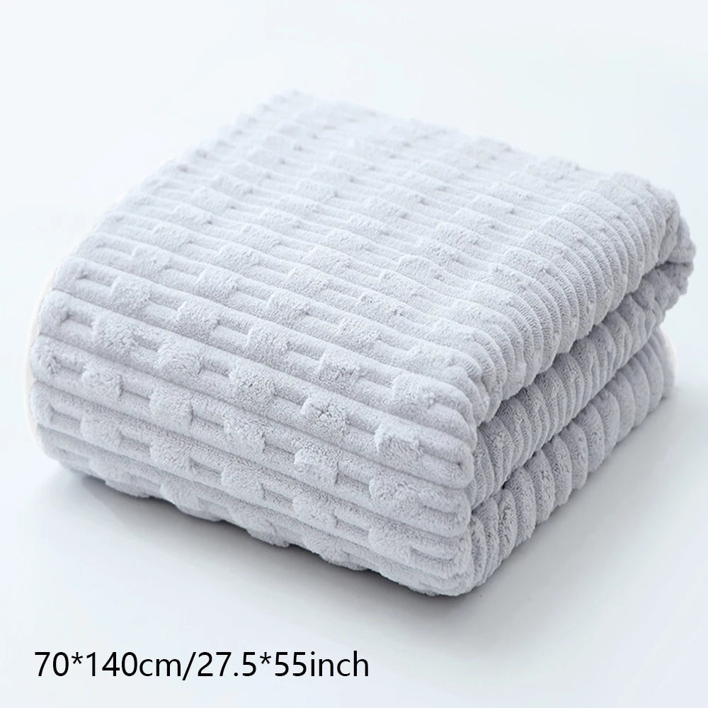 A stack of light gray coral velvet bath towels folded neatly on a white surface.