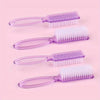 A set of four clear plastic nail art brushes with long handles and white bristles arranged on a pink background.