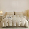 A beige quilted duvet cover set with matching pillowcases displayed on a bed against a light wall.