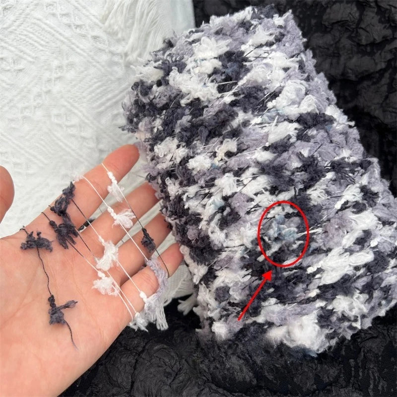 A close-up of hand-dyed variegated cotton blend yarn for knitting and crochet showing gray and white fibers.